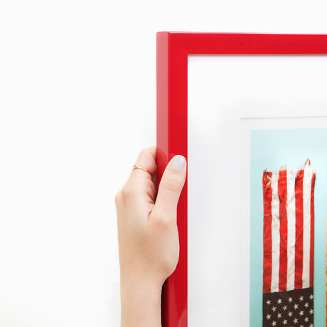 Hand holding ski and flag art in red frame at angle